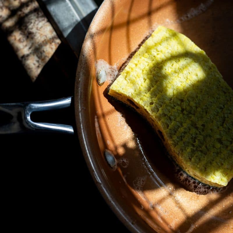 A sponge and cleaning products beside a metal pan. Illustrative stock photograph, not a photograph of the reviewed product.
