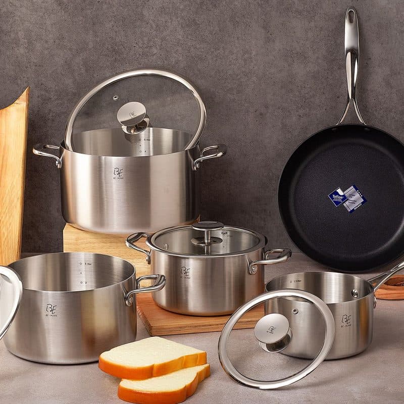 A dark-finished stainless steel cookware set with a cutting board. Illustrative stock photograph, not a photograph of the reviewed pan.