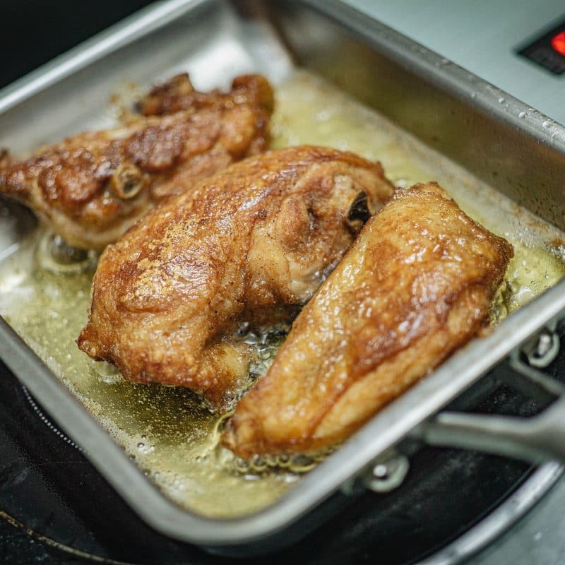 Food frying in a stainless steel pan. Illustrative stock photograph, not a photograph of a specific Tramontina pan.