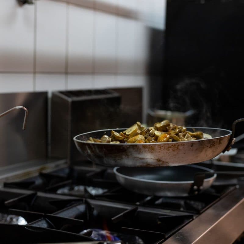 Mushrooms cooking in a stainless frying pan. Illustrative stock photograph, not a photograph of the reviewed pan.