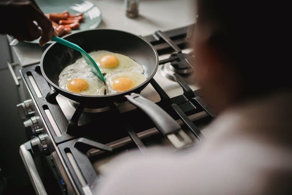 Eggs frying in a light-colored coated pan.
