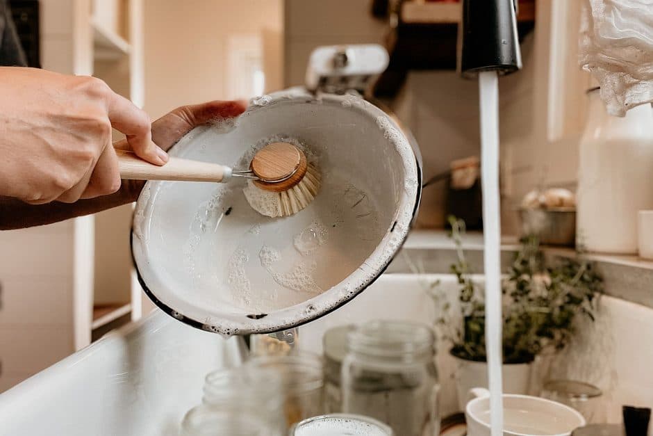 A person scrubbing a pan in a sink.