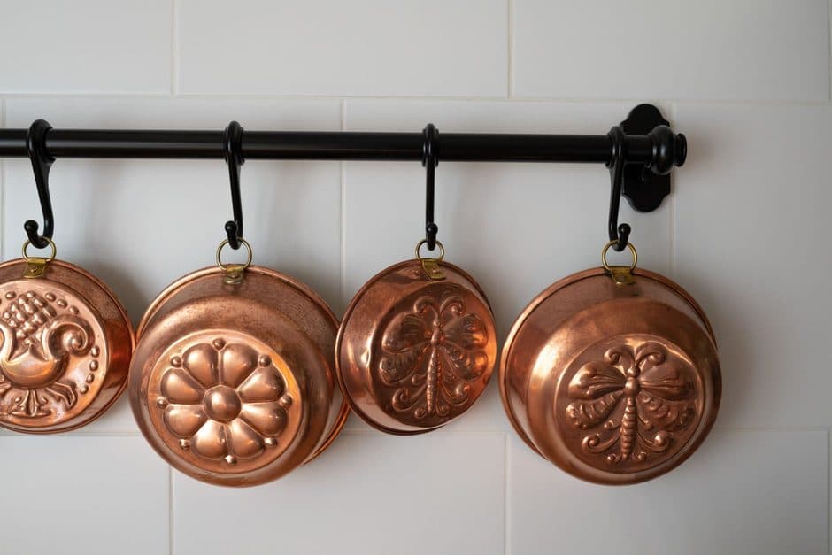 Copper cookware hanging on a kitchen wall.