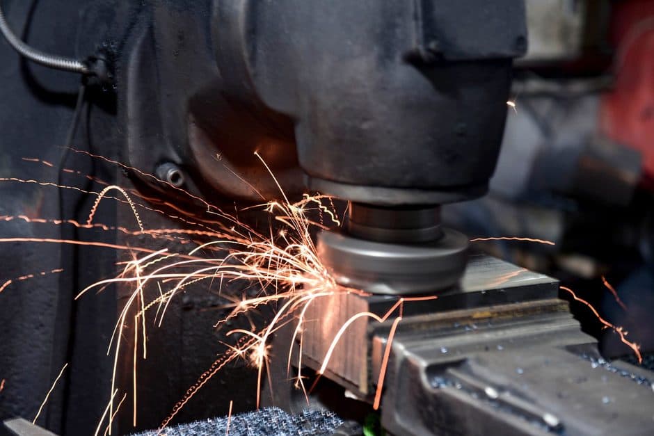 Sparks flying from metalworking machinery in a factory.