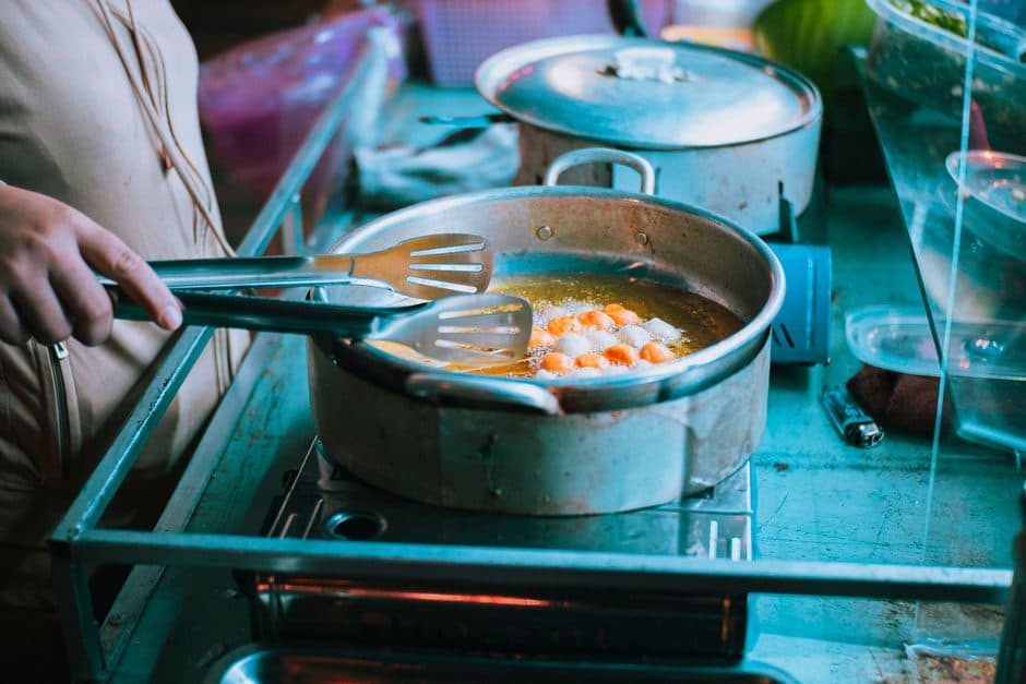 A person cooking carefully on a stovetop.