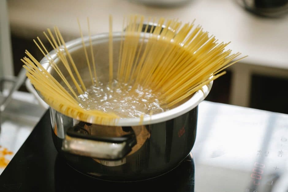Pasta cooking in boiling water in a stainless steel saucepan.
