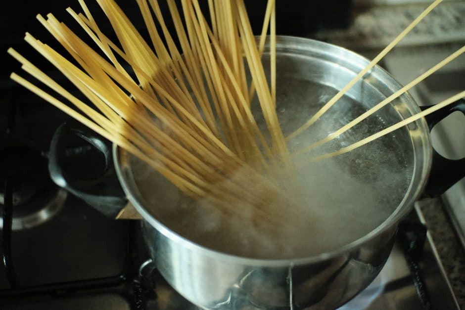 Pasta cooking in boiling water in a tall stainless steel pot.